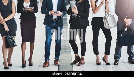 We are dressed for the occasion. a group of unrecognizable businesspeople standing in a row next to each other inside of the office during the day. Stock Photo