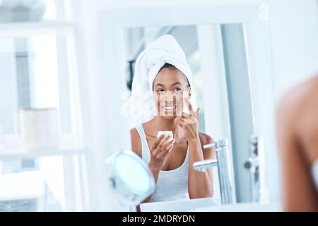 This is the best product on the market. a beautiful young woman applying moisturizer to her face. Stock Photo