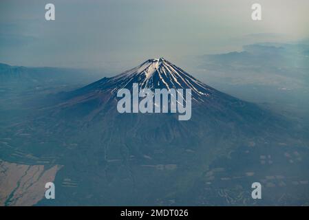 Mount Fuji silhouette, view from the plane. Snow crater of Fuji volcano. Stock Photo