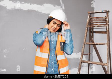 A young Indian construction worker holds her neck in pain from workplace injury Stock Photo