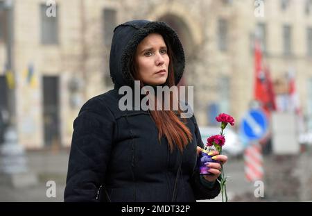 KYIV, UKRAINE - JANUARY 22, 2023 - A woman holds a carnation and a candle during the commemoration of the first fallen participants of the Revolution of Dignity as part of the annual Walk of Remembrance, Kyiv, capital of Ukraine. Stock Photo