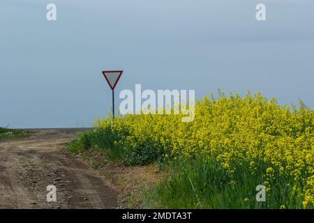 The sign Give way to the driver when exiting the highway at a rural intersection on the background Stock Photo