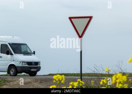 The sign Give way to the driver when exiting the highway at a rural intersection on the background of a passing car. Stock Photo