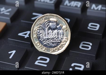 ONE POUND COIN ON CALCULATOR RE COST OF LIVING CRISIS MORTGAGES INFLATION INTEREST RATES THE ECONOMY ETC UK Stock Photo