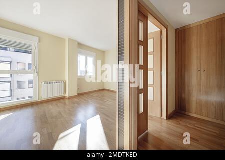 Empty room with light oak hardwood floors in a loft apartment with double glassed wooden doors and matching wooden built-in wardrobes Stock Photo