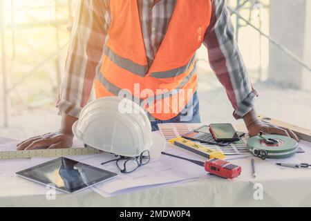 Engineer builder desk working space in construction site with floor plan or blueprint of building Stock Photo