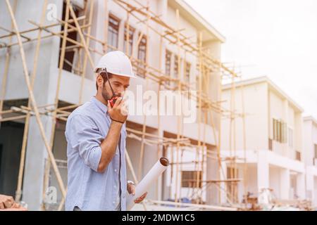 supervisor builder worker work in construction site. Architect home project chief engineer radio with floor plan. Stock Photo