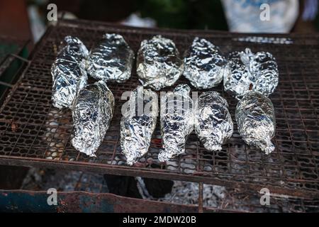 Meat Grilled in Foil on Flaming BBQ Grill. Barbecue cooking flaming grill  grid Food Background in aluminum foil. Portrait of the cooking food with  alu Stock Photo - Alamy