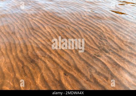 Seabed with wavy pattern on sand under shallow water, natural abstract background photo texture Stock Photo