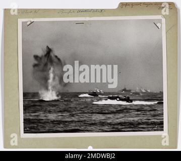 Photograph of Coast Guard Landing Craft Under Heavy Mortar Fire Off Coast of Philippines. Japs Greet Luzon Invaders With Heavy Mortar Fire. Coast Guard-manned LCVP's, packed with American troops, sweep through heavy surf in Lingayen Gulf to hit the beaches of Luzon in the Philippines on January 9. Heavy mortar fire was poured into the invasion craft by the Japs. At left, a mortar shell narrowly misses the two Coast Guard barges. Stock Photo