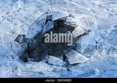 Hole in thin ice on a frozen lake, abstract winter background photo Stock Photo