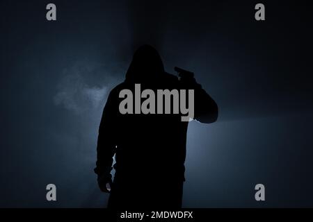 Suicide armed silhoulette man in dark forest at backlight Stock Photo