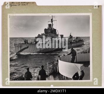 This image shows a Coast Guard cutter and a destroyer meeting at sea, likely for coordination during a maritime mission. The image highlights the partnership between the Coast Guard and Navy in various military operations. Stock Photo