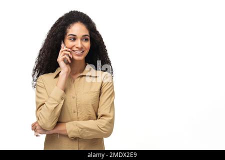 Satisfied carefree African-American woman with curly hair, talks via smartphone, has pleasant phone conversation with friend, enjoying speaking with someone, isolates on white Stock Photo