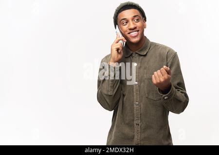 Carefree African-American young guy talking on smartphone isolated on white background, having phone conversation, cheerful man wearing casual shirt chatting Stock Photo