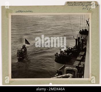 Moro Guerrillas Contact Coast Guard Ship Off Malabang. At dawn of the day that American forces established a beachhead on Malabang in the Philippines, a small craft approaches a Coast Guard combat cutter with Moro Guerrilla fighters and U.S. fliers to report to staff officers that the beach is cleared of Japs. This information enabled the invasion force to occupy the beach without the usual pre-invasion bombardment from heavy guns. Stock Photo