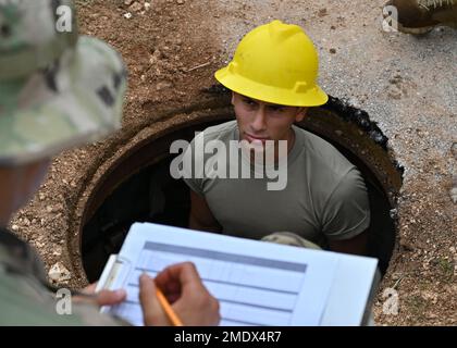 U.S. Air National Guard Senior Airman Ruben Flores, 212th Engineering Installation Squadron radar, airfield and weather systems journeyman, relays the telecommunication cables seen in a telecommunications maintenance hole to another team member on Andersen Air Force Base, Guam, July 26, 2022. Radar, airfield and weather system journeymen are responsible for installing, maintaining and repairing fixed and mobile radar, navigational aids, weather systems and radios. 36th Wing,Andersen AFB,EIS,Engineering Installation Squadrons,NGB,guam, Stock Photo