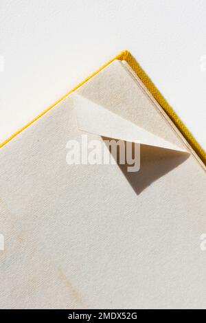 A dog-eared page in opened book on white table Stock Photo