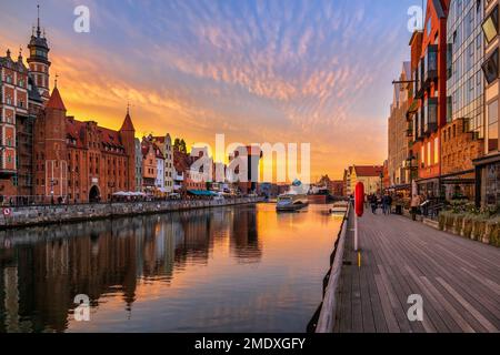 City of Gdansk after sunset in Poland. Old Town skyline from boardwalk promenade along Motlawa River at twilight. Stock Photo