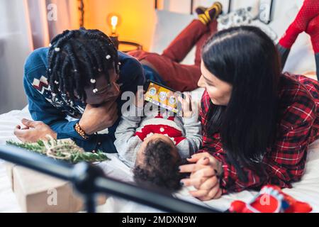 Toddler boy playing on the mobile phone with his parents supervising. High quality photo Stock Photo