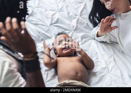 Overhead view of toddler boy lying on a bed with his parents on the sides. High quality photo Stock Photo
