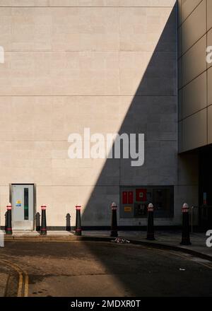 22 Jan 2023 - LondonUK: Shadow against plain wall and door of modern building on sunny day in city urban street Stock Photo