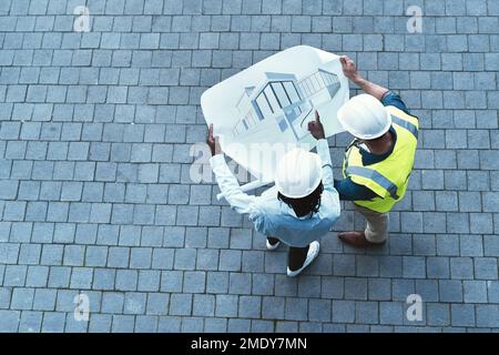 I assure you that everything will go according to plan. High angle shot of two engineers looking at a blueprint. Stock Photo