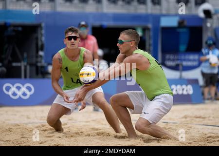edgars tocs right of latvia returns a shot as teammate martins plavins watches during a mens beach volleyball bronze medal match against qatar at the 2020 summer olympics saturday aug 7 2021 in tokyo japan ap photofelipe dana 2mdydam