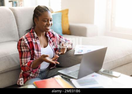 Black woman having online briefing session from home, using laptop Stock Photo