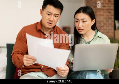 Concerned mature man and young woman sitting on couch with laptop, checking bills, working on family budget together Stock Photo