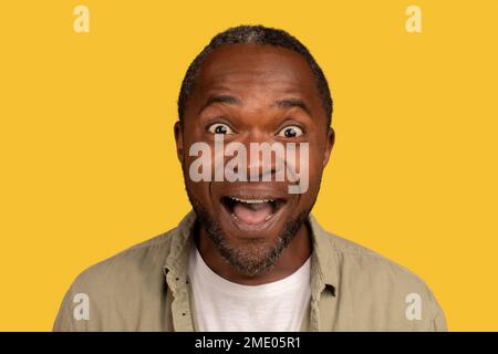 Portrait of glad surprised african american middle aged man with open mouth, looking at camera Stock Photo