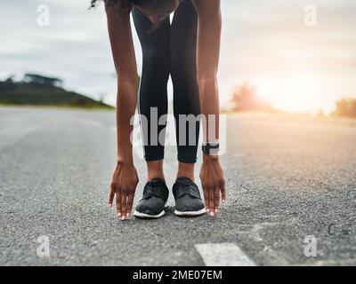 Stretch it out. an unrecognizable young sportswoman warming up for a workout outdoors. Stock Photo