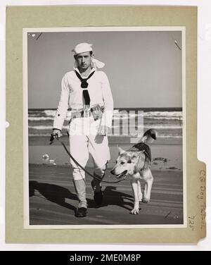 Coast Guard Dog Patrol. This image depicts a Coast Guardsman and his serious dog make their patrol down a lonely stretch of coastline. Stock Photo