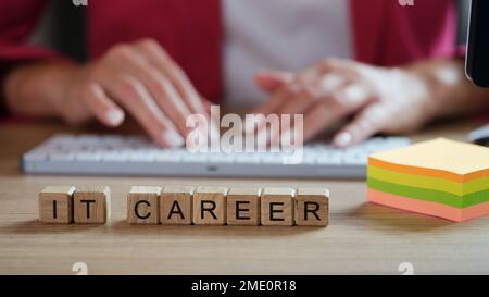 IT career words collected from cubes and note papers, programmer typing on keyboard in background. Stock Photo