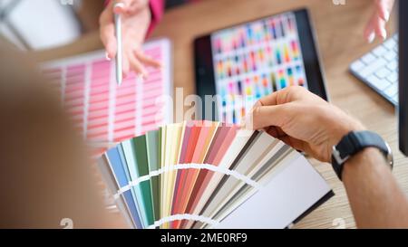 Client chooses color from variety of samples in art studio close up. Stock Photo