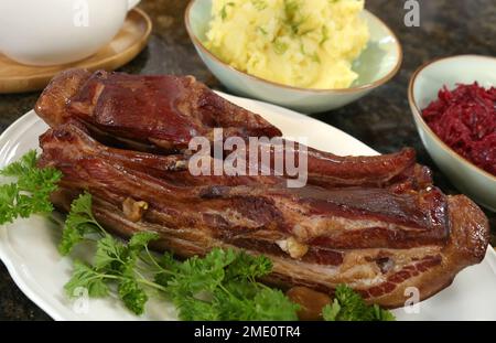 Smoked bacon cooked and served with mushed potatoes and fried grated beets. Stock Photo