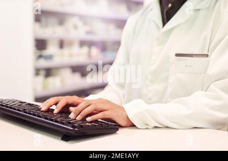 Your information is safe with us. a pharmacist working on a computer in a pharmacy. Stock Photo