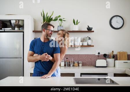 How bout some breakfast my love. a happy middle aged couple embracing in the kitchen at home. Stock Photo