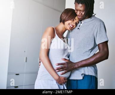 Hows my baby doing today. a young man touching his pregnant wifes belly. Stock Photo