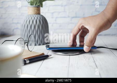 charging Smartphone using Wireless Charging Pad, top view  Stock Photo