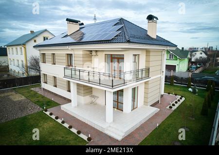 Home residence with solar panel system for generating electricity through photovoltaic effect. New two-storey house with solar modules on roof. Ecological renewable energy sources concept. Stock Photo