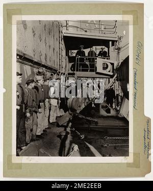 Merchant Marine Inspection. Aboard a cargo vessel in a far eastern port, officers and men of the Coast Guard Merchant Marine inspection division conduct a shipboard inspection, as crew and officers of the ship stand mustered on the deck.