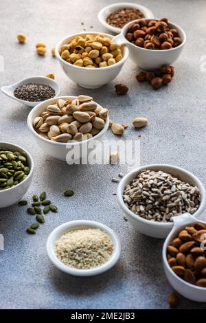 From above bowls full of nuts and seeds on concrete background Stock Photo