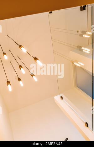 From below glowing light bulbs hanging on wires on ceiling in hallway of contemporary house Stock Photo
