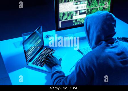 Hes in the hacking zone. a young male hacker cracking a computer code in the dark. Stock Photo