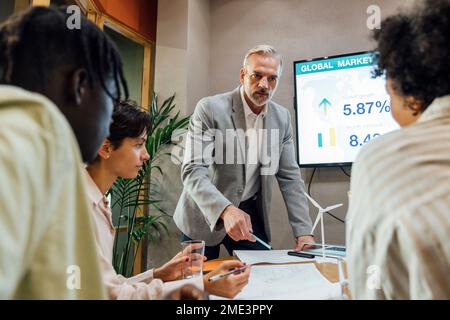 Businessman with colleagues discussing over documents in office Stock Photo