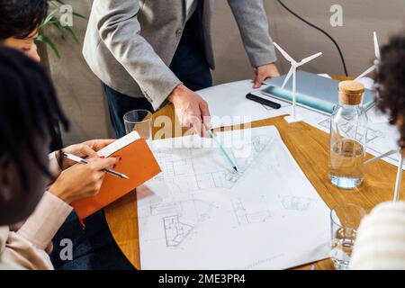 Businessman discussing over blueprints with colleagues in office Stock Photo