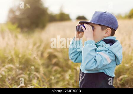 Boy looking through binoculars on field Stock Photo