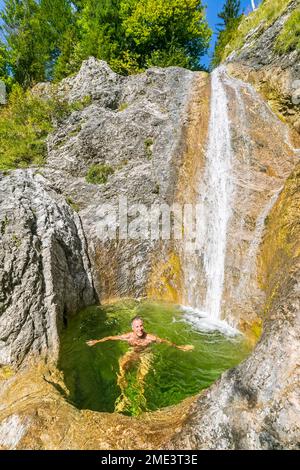 Germany, Bavaria, Male tourist relaxing in small pond of Rappinbach waterfall in summer Stock Photo