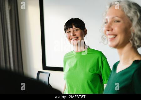 Two happy colleagues in green clothing in office Stock Photo